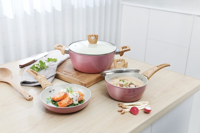 "Modern ceramic nonstick frying pan with wooden handle on a white marble counter"