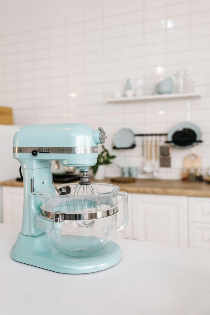 A mint green stand mixer on a kitchen counter with minimalist decor and white tiles.